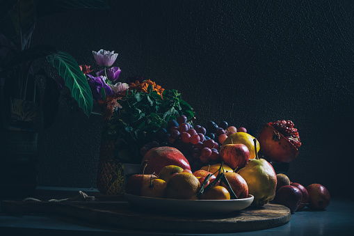 Dark baroque renaissance style still life photography of fruit and flowers. Apples, grapes, pomegranate, quince, mint and garden flowers. High quality photo