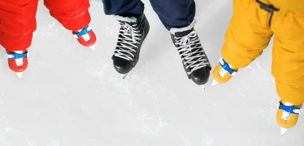nahaufnahme der schuhe von papa und kindern beim schlittschuhlaufen auf der eisbahn - ice skating ice hockey child family stock-fotos und bilder