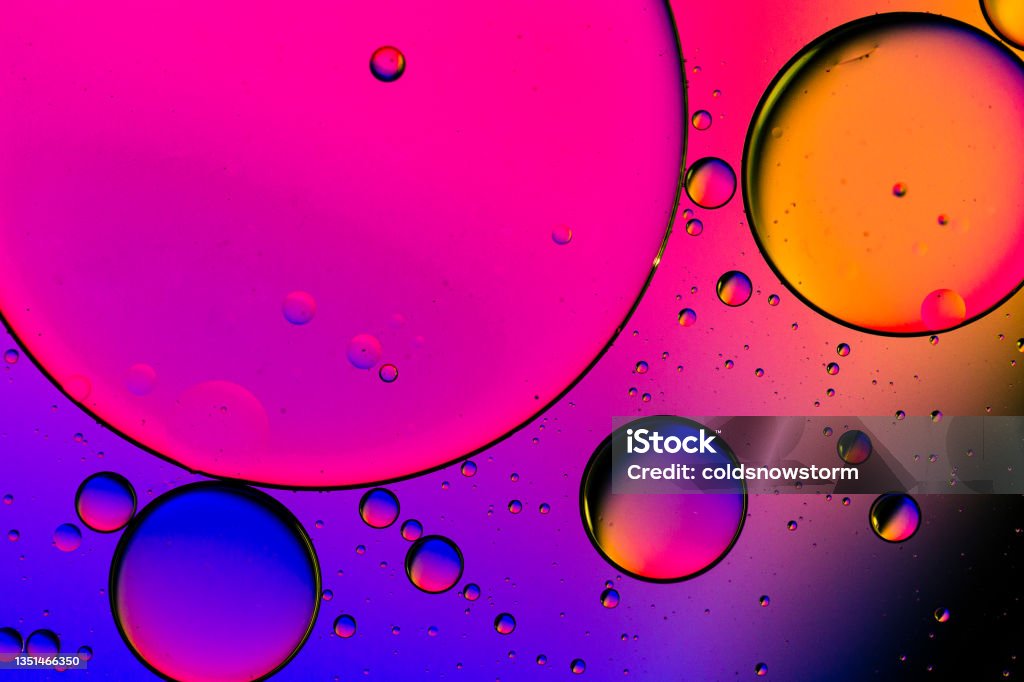 Macro oil and water multi colored abstract background Close up macro image depicting droplets of oil in water on a multi colored background. The oil forms interesting circles and spheres in the water, and colorful background produces an abstract effect. Abstract Stock Photo