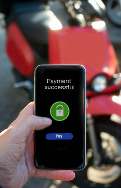 Man's hand pays the rental of electric motorcycle with application on his phone stock photo