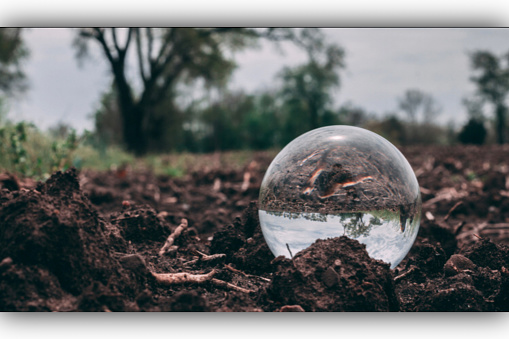 Crystal ball sitting on the earth”s surface of dirt with amazing scenery close-up shot with background nature landscape
