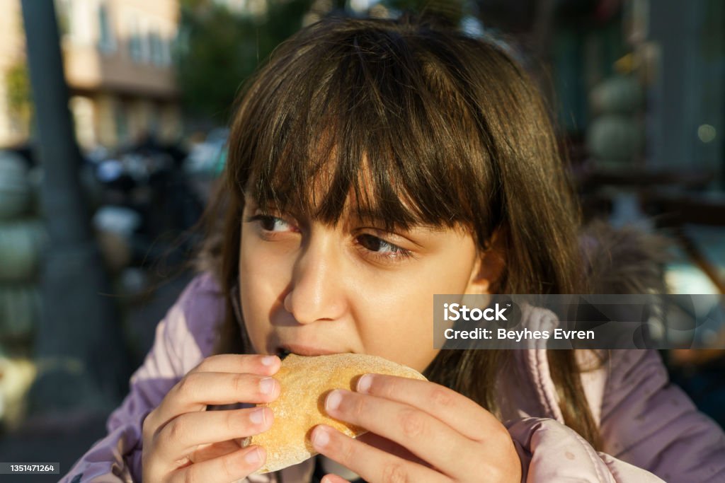 Beautiful cute little caucasian girl  with hamburger Eating, Child, Unhealthy Eating, Hamburger, Fast Food Obesity Stock Photo