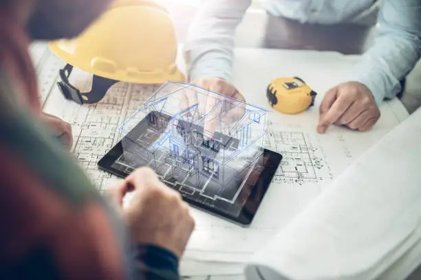 Architect and his client looking at the hologram of a house project over a tablet computer. The client is reviewing his future house layout
Note to inspector: I am the author of the building project