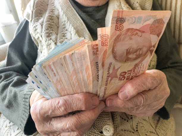 closeup wrinkled hands of a senior person holding some Turkish Lira stock photo