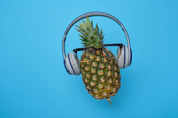 istock A fresh ripe pineapple wearing wireless headphones on blue background. 1351474765