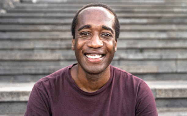 istock Happy African man smiling into the camera while sitting on urban stairs 1351476360