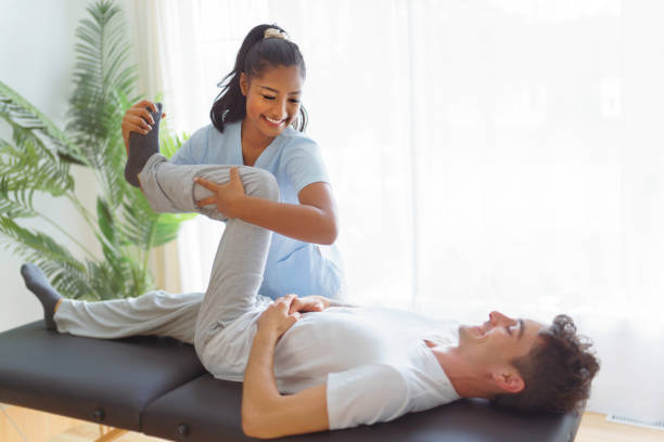 Young woman physiotherapist at physio clinic with customer stock photo