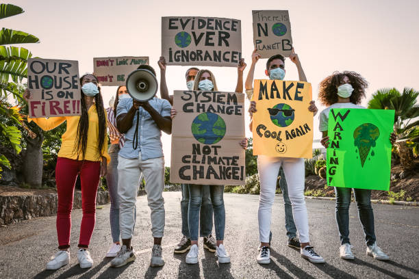 Group of activists protesting for climate change during covid19 - Multiracial people fighting on road holding banners on environments disasters - Global warming concept stock photo