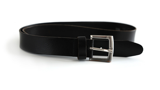 Cinturón de cuero viejo con hebilla de metal que se encuentra frente a un fondo blanco photo