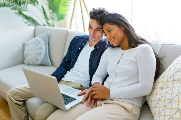 istock Young couple relaxing on sofa with laptop 1351477325