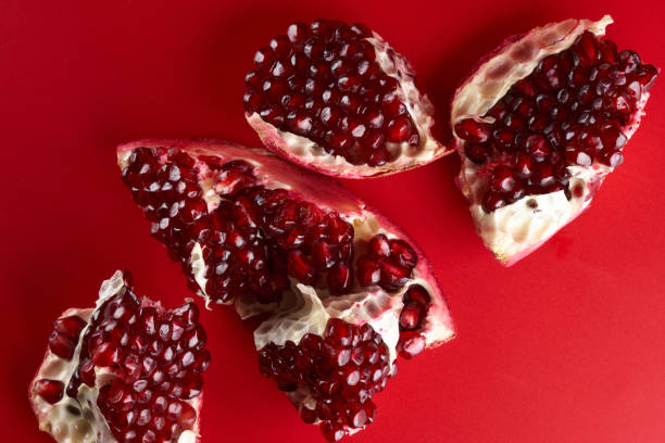 istock Ruby ripe fresh juicy sliced pomegranate isolated on red background 1351477720