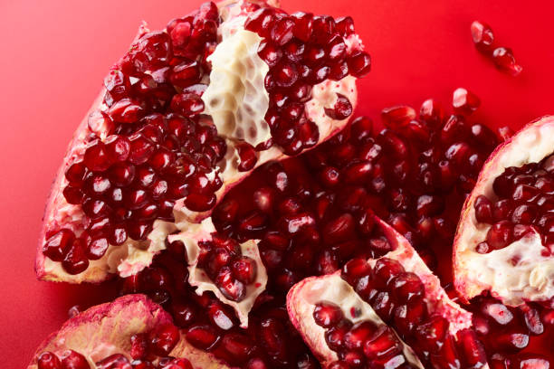 istock Ruby ripe fresh juicy sliced pomegranate isolated on red background 1351478269