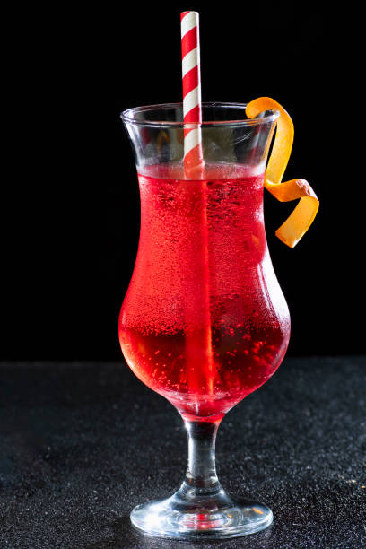 a red cocktail glass, long drink with a red and white straw, on a dark background a red cocktail glass, long drink with a red and white straw, on a dark background club soda stock pictures, royalty-free photos & images