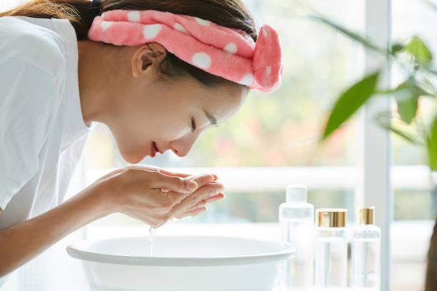 young asian woman washing her face - gezicht wassen stockfoto's en -beelden