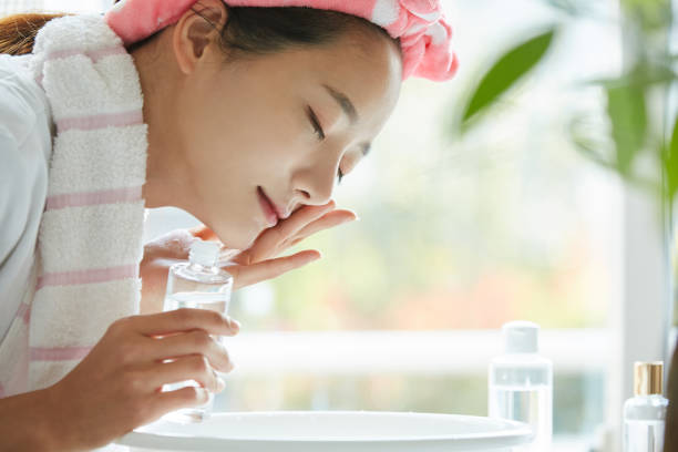 giovane donna asiatica che si lava il viso - detergente per il viso foto e immagini stock