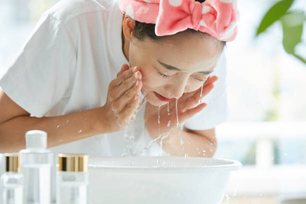 young asian woman washing her face - gezicht wassen stockfoto's en -beelden