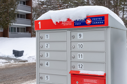 Ottawa, Canada - January 22, 2021: Canada Post mailbox with red sign in English and French near house in winter season