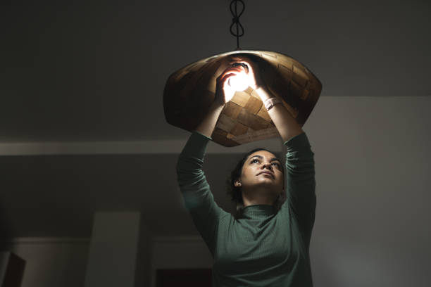 mujer cambiando lámpara en casa - led lighting equipment light bulb installing fotografías e imágenes de stock