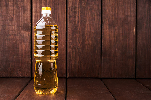 Plastic bottle of vegetable sunflower olive oil isolated on wooden kitchen background