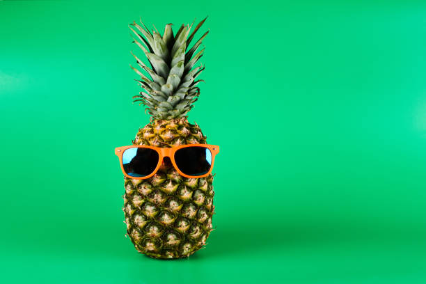 istock Pineapple in sunglasses isolated on green background with copy space. Summer vacation concept and travel to warm countries, tropical fruit art 1351490079