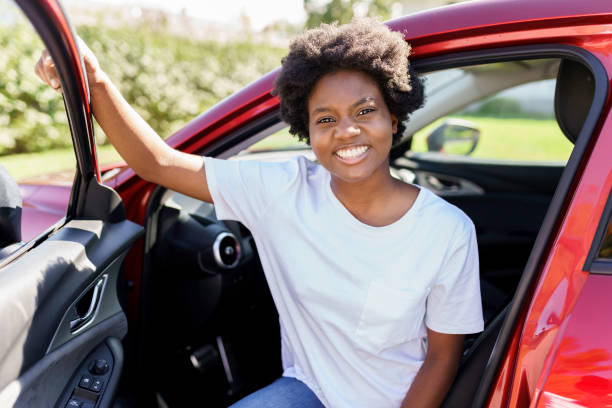 istock Young black woman sit on is first red car 1351490435