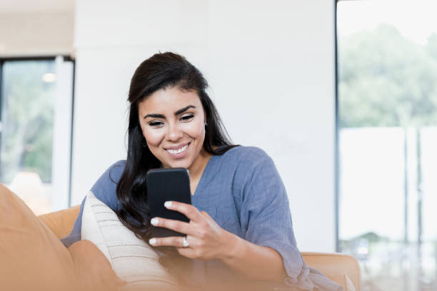 istock Cheerful woman uses smartphone while relaxing at home 1351490514