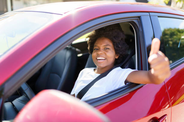 istock Young black woman sit on is first red car 1351490586