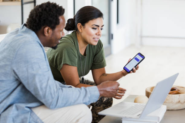Female soldier and her husband reviewing home finances A female soldier and her husband use a banking app to check the state of their finances before the woman leaves for a military assignment. military lifestyle stock pictures, royalty-free photos & images