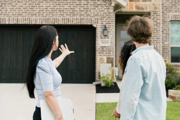 istock Real estate agent gestures while describing house features to couple 1351490855
