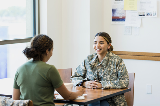 A young female soldier talks with a military counselor. The counselor takes notes while talking with the soldier.