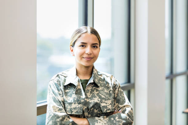 Portrait of cheerful female soldier A confident female soldier stands with her arms crossed while working in a recruitment office. war veteran stock pictures, royalty-free photos & images