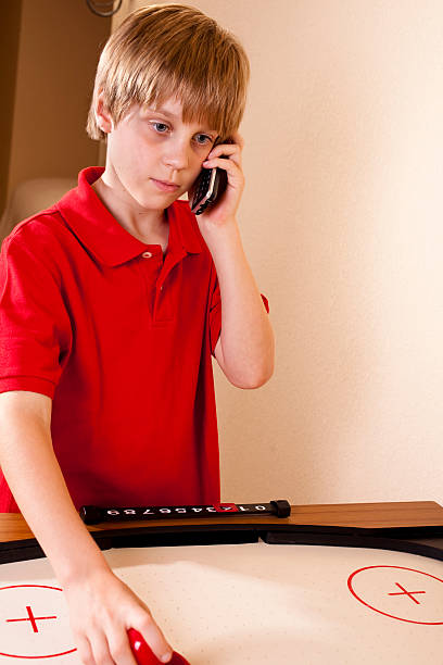 istock Boy playing air hockey, talking on phone, 135149194