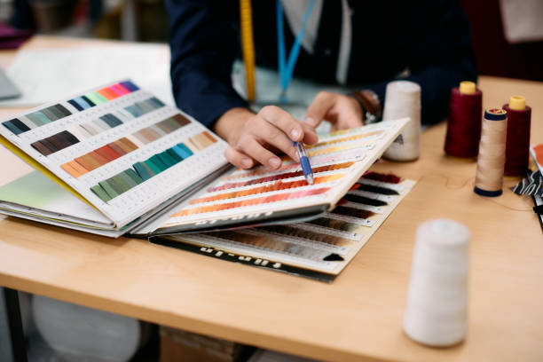 istock Close-up of fashion designer choosing fabric samples while working at clothing design studio. 1351492285