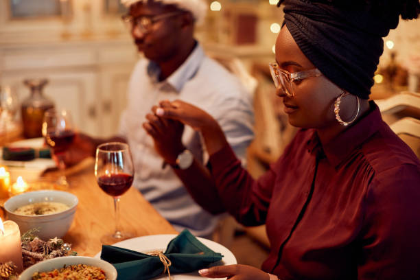 食卓でクリスマスディナーの前に恵みを言うアフリカ系アメリカ人のカップル。 - praying saying grace dinner meal ストックフォトと画像