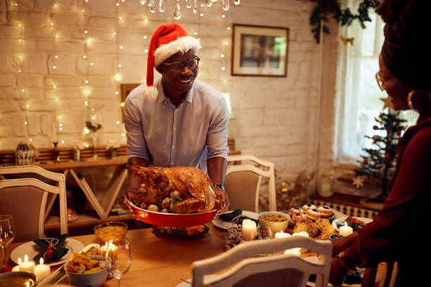istock Happy black man serving Christmas turkey during dinner at dining table. 1351492407