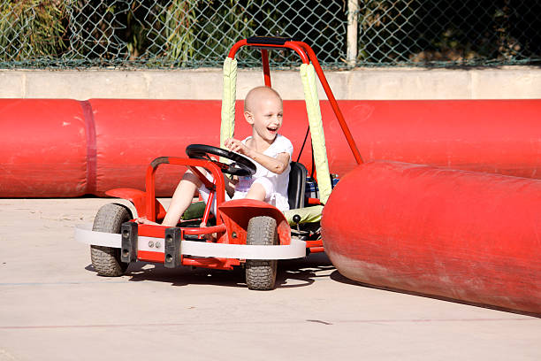 Little boy having fun sliding down a yellow and red slide while sitting in a burlap sack