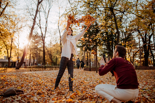 Happy young couple playing and laughing together in autumn park