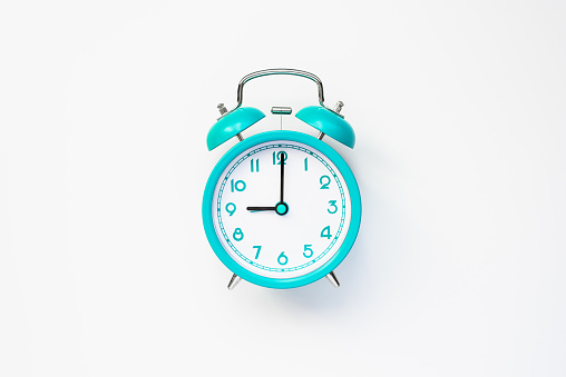 Reloj despertador moderno en estilo retro sobre baterías de color cian aisladas sobre fondo blanco. Concepto de tiempo y mañana. Estación plana. photo