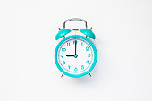 Modern alarm clock in retro style on cyan color batteries isolated on white background. Time and morning concept. Flat lay.