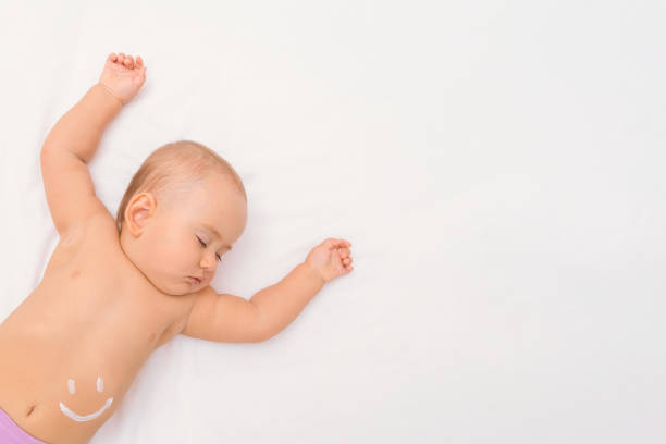 istock Sleeping newborn on a white sheet, copy space. A baby sleeps with a smiley face painted with moisturizer on his stomach 1351504283