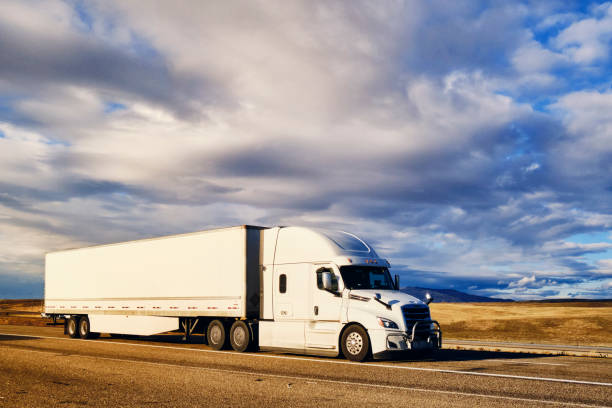 Long Haul Semi Truck On a Rural Western USA Interstate Highway Large semi truck hauling freight on the open highway in the western USA under an evening sky. semi truck stock pictures, royalty-free photos & images