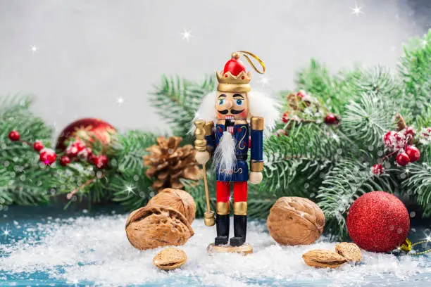 Christmas nutcracker toy soldier on Christmas background with fir tree branches, nuts, xmas balls. Christmas of New Year Greeting Card. Copy space