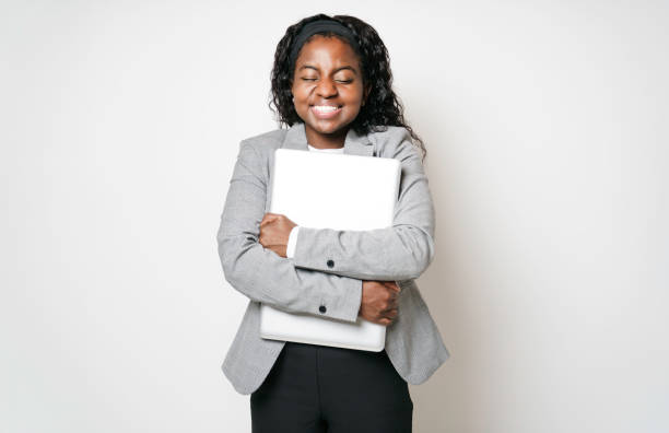 コ�ンピュータを保持している幸せな黒人ビジネスウーマンの孤立したショット - businesswoman black african descent studio shot ストックフォトと画像