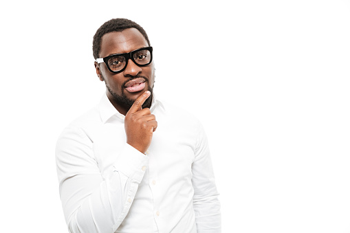 Photo of serious young african man dressed in shirt wearing glasses standing isolated over white background.