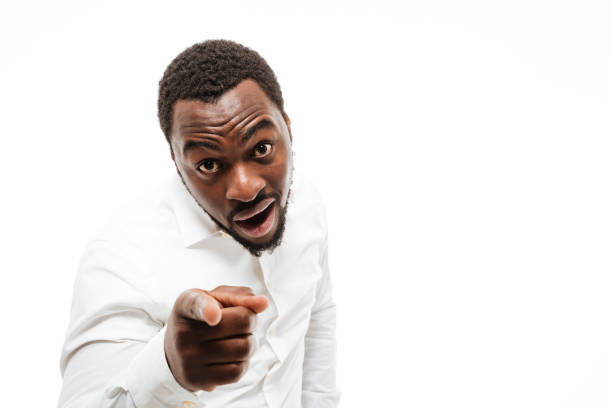 istock Happy young african man dressed in shirt pointing at camera 1351517290