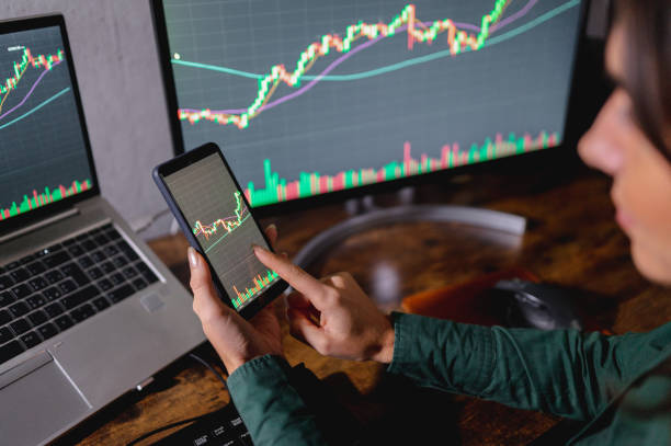 istock business woman sitting at desk comparing many charts and graphs on computer desktop and smart phone. 1351523032