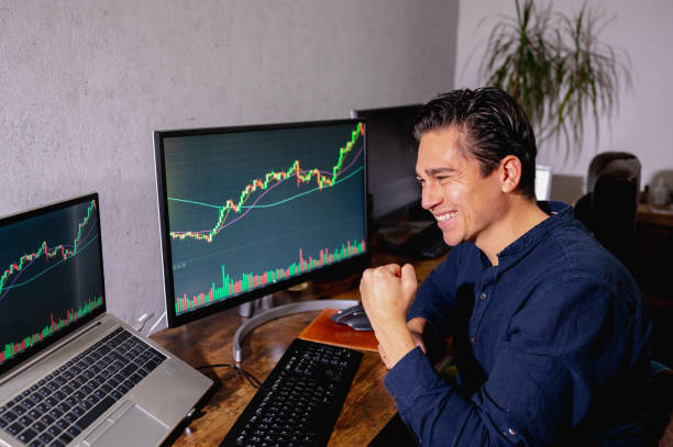 istock Side view young business man exulting sitting on his desk looking chart on computer. 1351523059