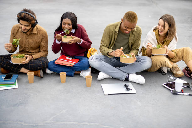 Students eating salad during lunch on asphalt