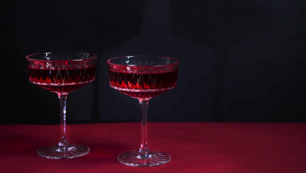 istock Two red wine glasses on a black background with copy space for your text.tempting offer advertising red wine. wine list. restaurant advertising. a bright combination of red and black. romantic dinner 1351537315