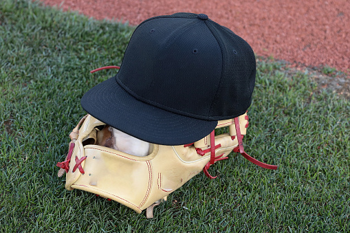 baseball glove and hat on green grass